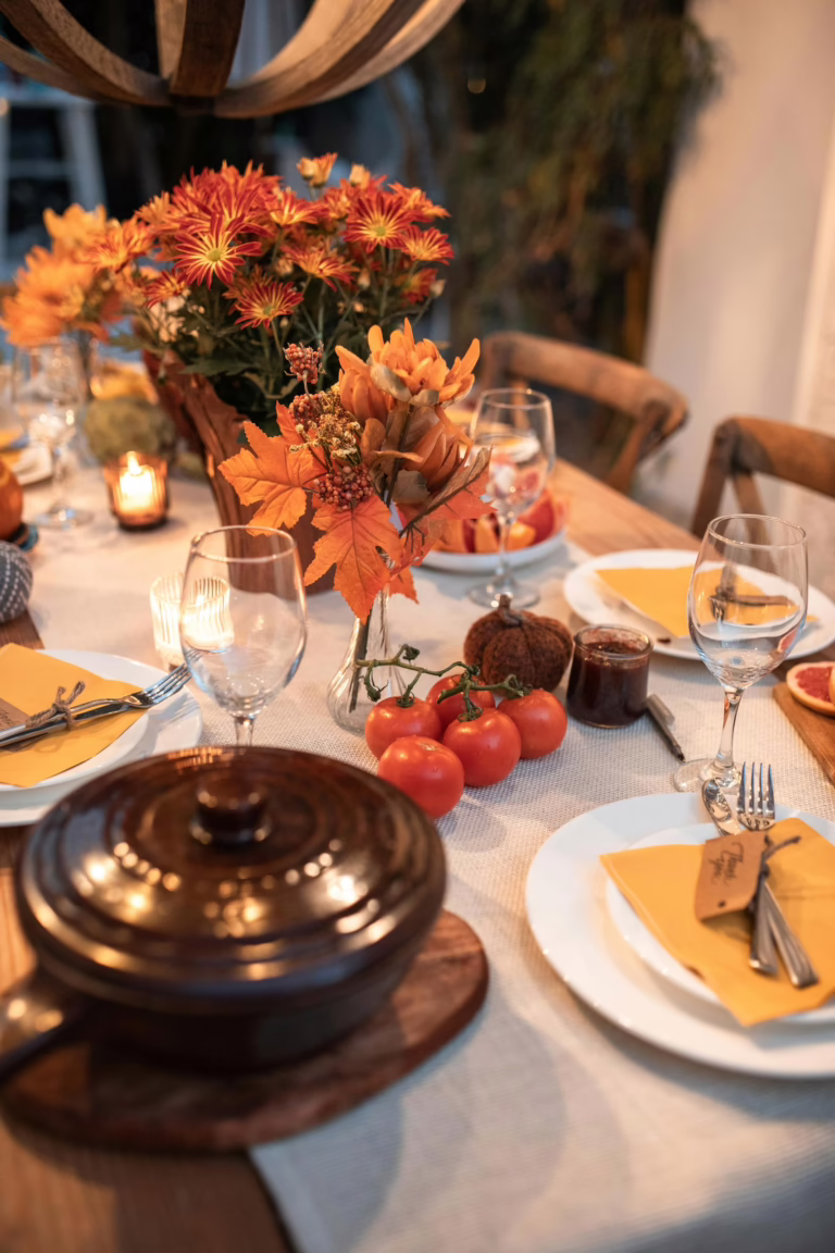Warm autumn table setting with flowers, candles, and dinnerware. Perfect for family gatherings.
